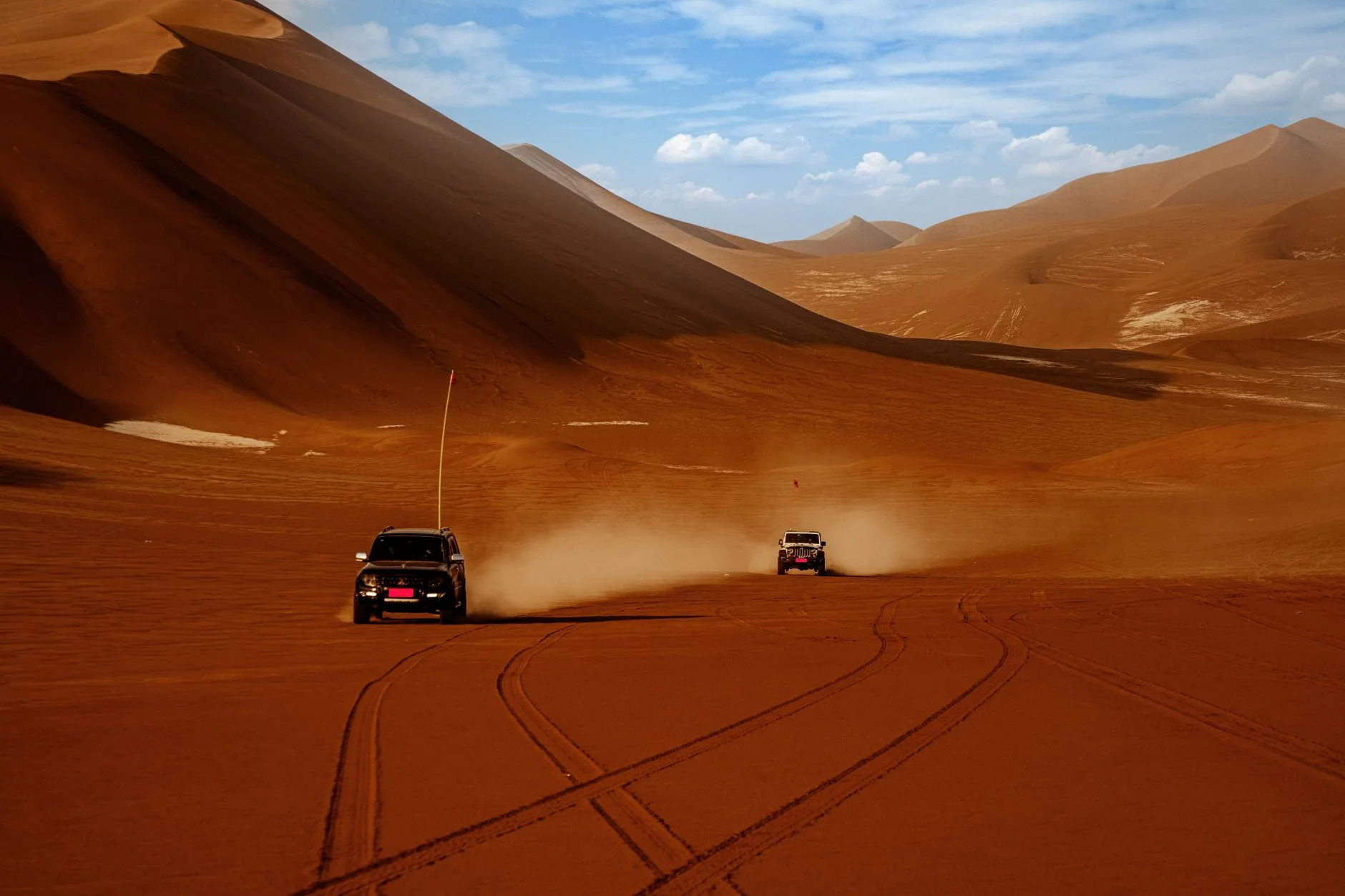 4x4 blanc garé sur une piste de gravier rouge en Namibie sous un ciel bleu intense