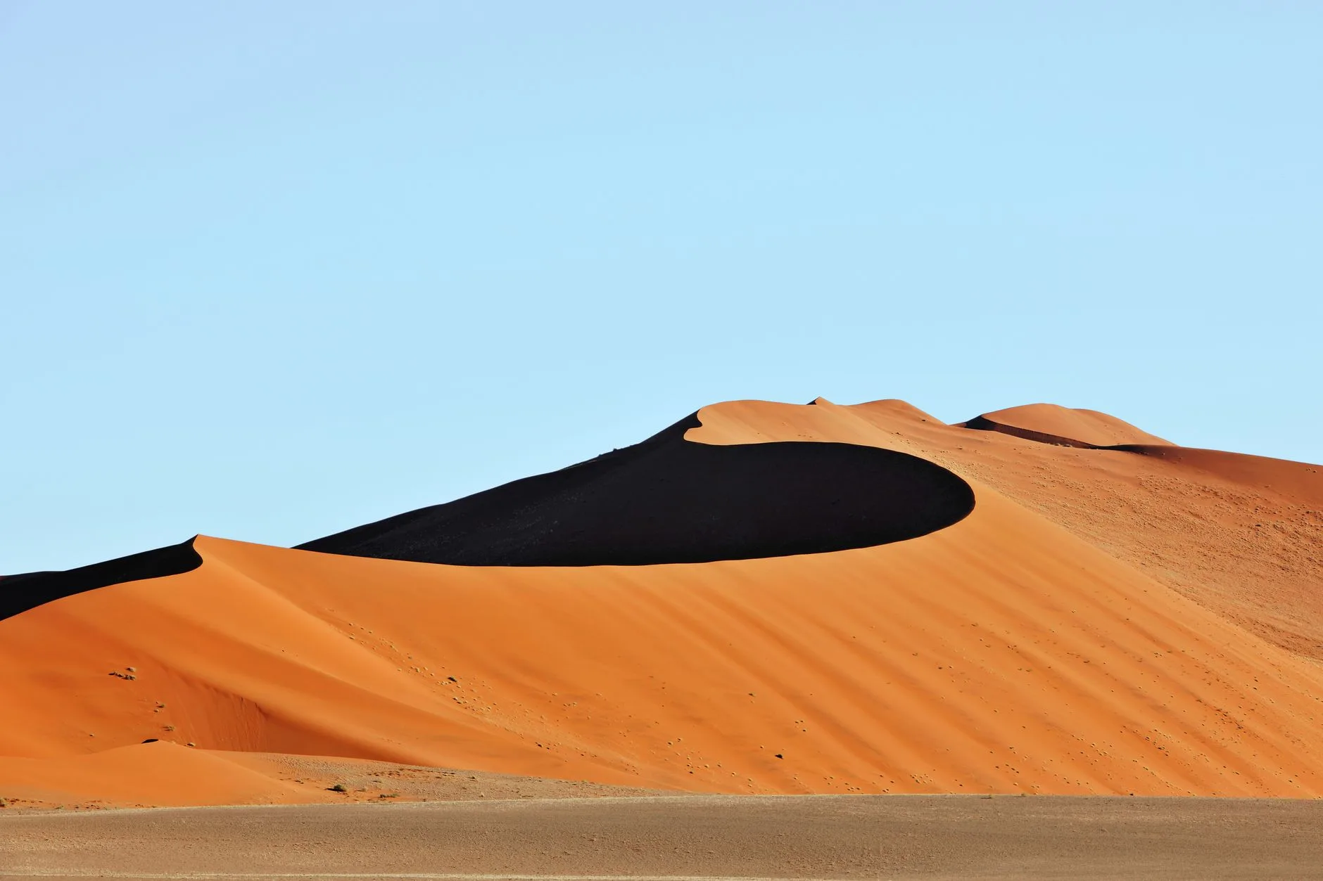 Route namibienne traversant le désert du Namib avec dunes orangées et ciel bleu profond